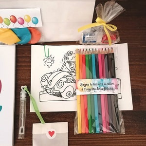 May include: A coloring book with a cartoon car and a set of colored pencils in a clear plastic bag. The bag has a tag that says "Sogno la tua vita a colori, e il segreto della felicita."