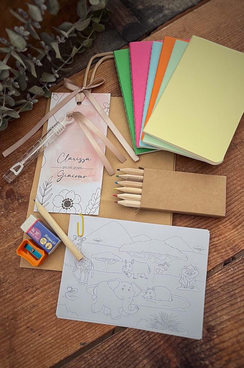 May include: A collection of party favors including small notebooks in various colors, a coloring book with safari animals, colored pencils, a pencil, eraser, and sharpener. A tag with the names Clarissa and Giacomo is also included.