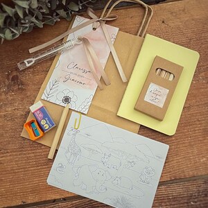May include: A brown paper gift bag with a watercolor tag, a coloring book, crayons, a yellow notepad, a pencil, a sharpener, and an eraser. The tag has the names Clarissa and Giacomo, and the date 26.09.2026.