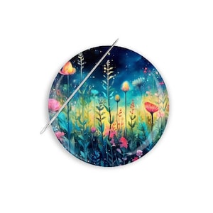 May include: A round decorative plate featuring a watercolor painting of a colorful meadow with tall flowers and a starry night sky. A silver metal needle is placed diagonally across the plate.