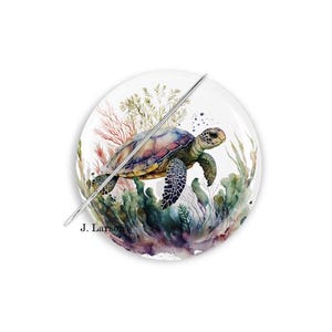 May include: A round decorative plate featuring a watercolor painting of a sea turtle swimming in an underwater scene. The turtle has a green and brown shell, with a detailed design. The plate includes the text "J. Larson's".