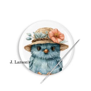 May include: A blue bird wearing a straw hat with a pink flower. The bird is looking at the camera. The image is on a white background.