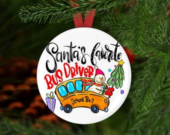 Può includere: Ornamento natalizio rotondo bianco con la scritta "Santa's favorite Bus Driver". L'ornamento presenta un pupazzo di neve che guida un autobus scolastico giallo, un albero di Natale e un regalo confezionato. Un nastro rosso è attaccato per appenderlo.