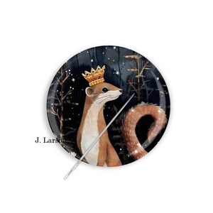 May include: Round decorative plate featuring a weasel wearing a gold crown and holding a silver wand. The background is a dark blue night scene with trees and stars. The plate has the text "J. Larson".