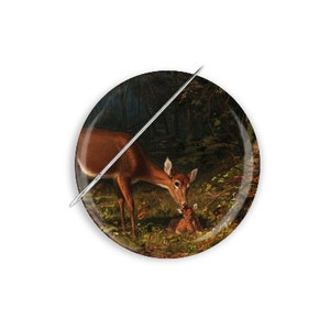May include: A button featuring a painting of a doe and fawn in a forest setting. The doe is brown with white markings and is looking down at the fawn. The fawn is lying on the ground and is looking up at the doe. The background is a dark green forest with some light coming through the trees.