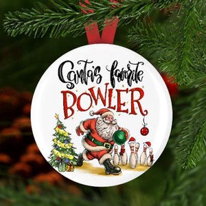 May include: White round Christmas bauble featuring a red, white and green illustration of Santa Claus bowling. The bauble reads "Santa's favourite bowler".