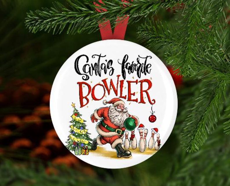 May include: White round Christmas bauble featuring a red, white and green illustration of Santa Claus bowling. The bauble reads "Santa's favourite bowler".