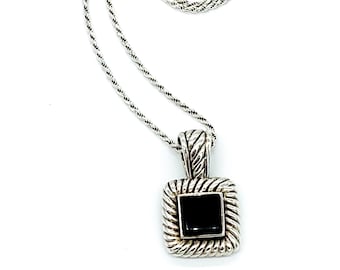 Può includere: Una collana d'argento con un ciondolo quadrato con una pietra preziosa nera. Il ciondolo ha un design a corda attorno ai bordi.