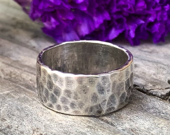 May include: A silver hammered band ring. The ring is wide and has a textured surface.