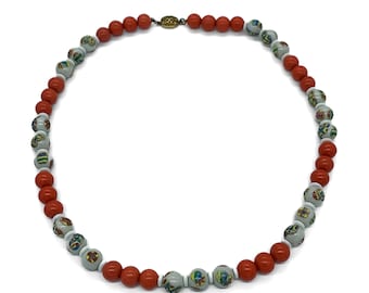 May include: A necklace made of alternating red and white beads. The white beads have a colourful floral pattern.