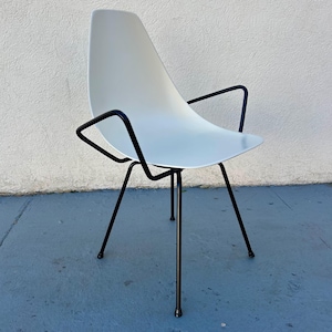 May include: A white plastic chair with black metal legs and arms. The chair has a unique, curved design.