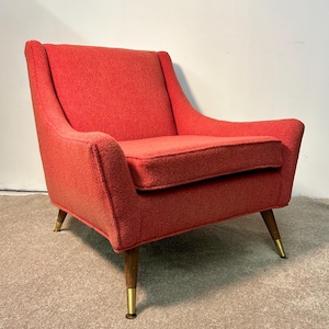 May include: A mid-century modern armchair in a vibrant coral hue. The chair features a high back, curved arms, and a cushioned seat. The wooden legs have brass-colored tips. This vintage-style chair is a statement piece for any living space.