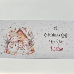 May include: A rectangular Christmas gift card with a winter scene featuring three snowmen in hats and scarves, a gingerbread house, and the text "A Christmas Gift For You Willow."