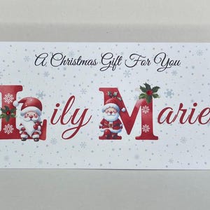 May include: A rectangular Christmas gift card with the text "A Christmas Gift For You" and the name "Lily Marie". The letters are red and decorated with Santa Claus illustrations and snowflakes.