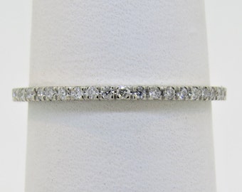 May include: A thin silver band with a row of small, clear diamonds set in a pave setting.