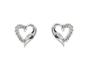 May include: A pair of silver heart-shaped earrings with small clear stones set around the edge of each heart.