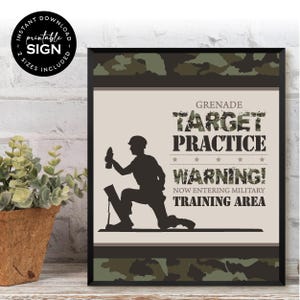 以下が含まれることがあります： 軍事テーマの額入りプリント。プリントには、手榴弾を持った兵士のシルエットが描かれており、「Grenade Target Practice Warning! Now Entering Military Training Area.」というテキストが書かれています。