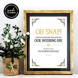 May include: A gold and black wedding sign with the text "Oh Snap! Help us capture the love on our wedding day. Kindly tag #yourwedding."
