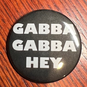 May include: A black button with white text that reads "Gabba Gabba Hey".