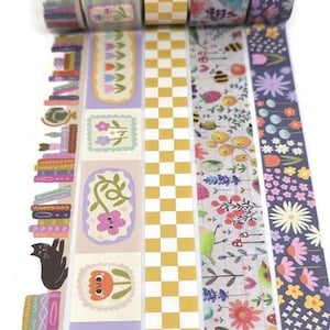 May include: A collection of decorative washi tape rolls featuring various designs. Patterns include floral motifs, checkerboard, and illustrated scenes with books and cats. The color palette is soft, with pastel pinks, purples, yellows, and greens.