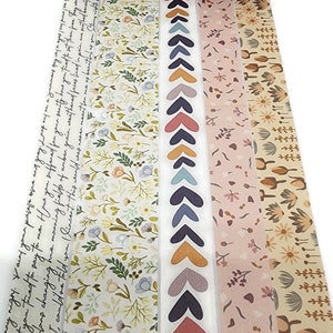 May include: A set of five washi tapes featuring floral and heart patterns. The tapes are in shades of pink, yellow, blue, brown, and white.