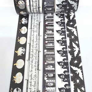 May include: Five rolls of decorative washi tape featuring distinct black and white patterns. Designs include gold-accented pumpkins, cursive text, stacked books with floral details, hooded figures with skulls, and silhouettes of bats and spiders.