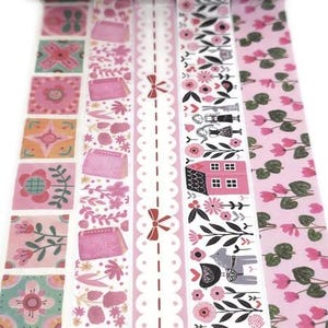 May include: Decorative washi tape rolls in various pink patterns. Designs include floral, houses, birds, and geometric shapes. The tape is ideal for scrapbooking, journaling, and crafting projects. The rolls are displayed vertically.