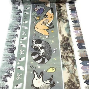 May include: Decorative washi tape rolls featuring various nature-themed designs. The rolls display illustrations of animals like foxes, raccoons, and opossums, along with forest and cityscape patterns. The color palette includes greens, browns, and whites.