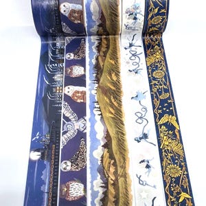 May include: Five rolls of decorative washi tape featuring distinct patterns: a night train scene, a series of owls on a dark blue background, a rolling green landscape, small blue fairy figures on a white background, and gold floral motifs.