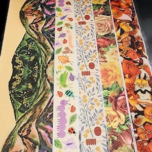 May include: Five rolls of decorative washi tape with different designs. The designs include a mountain range, a caterpillar and other insects, a floral pattern, a branch with leaves and berries, and a fox pattern.