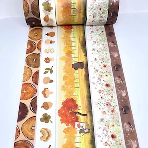 May include: Five rolls of decorative adhesive tape featuring distinct patterns: a repeating bagel design, a column of various mushrooms and acorns, a landscape with trees and a small animal, a field of wildflowers, and a brown strip with teapots.