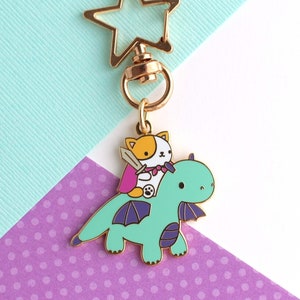 Enamel keychain with star shaped swivel key ring of a orange and white cat with cape and sword riding a turquoise dragon