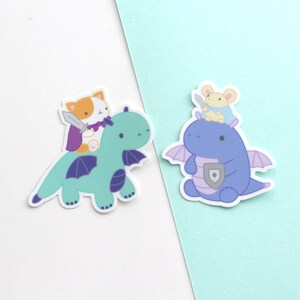 Sticker of a cat with cape and sword riding a dragon and sticker of mouse with cape and sword riding a dragon