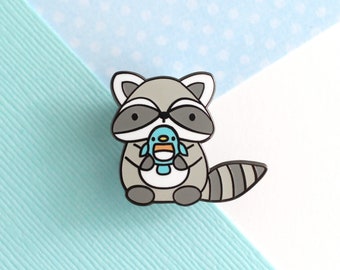 Raccoon Enamel Pin. Raccoon holding Blue Bird Enamel Pin. Cute Raccoon and Little Blue Bird Friend Pin. Hat, Jacket or Lapel Pin