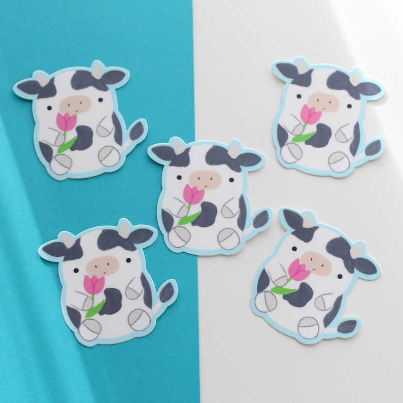 May include: Five black and white cow stickers with pink flowers. Each sticker has a light blue outline.