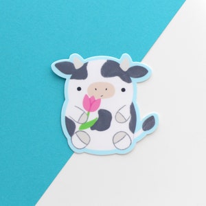 Vinyl sticker of a standing black and white cow holding a pink tulip
