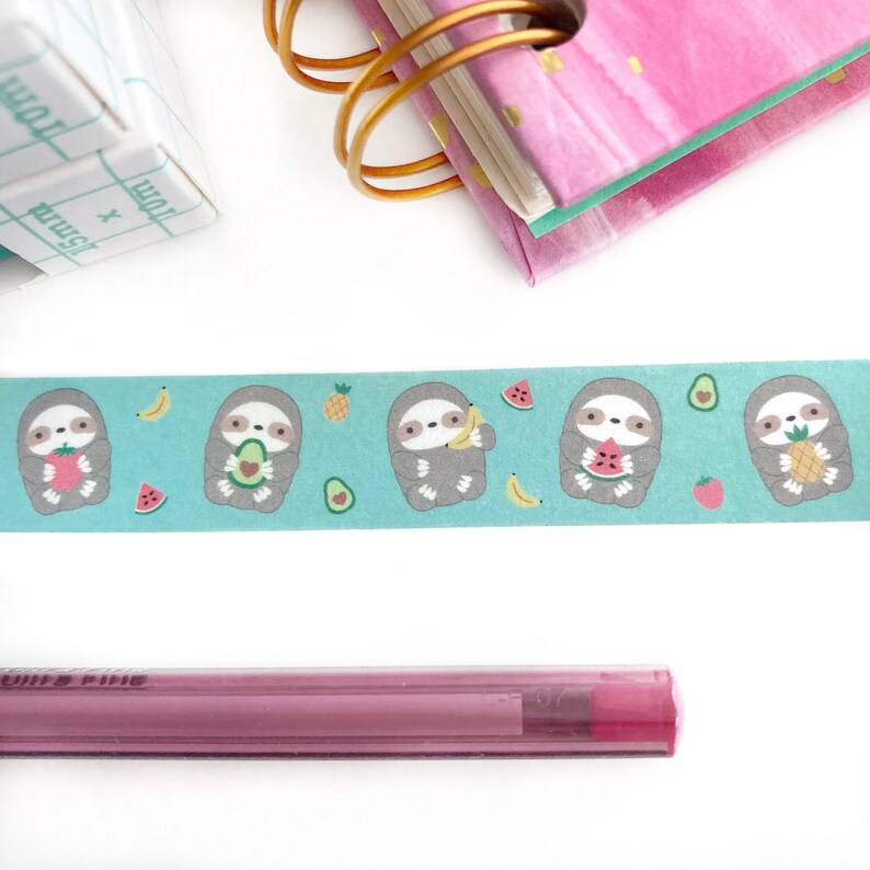 May include: A turquoise washi tape with a repeating pattern of sloths eating fruit. The sloths are gray and have brown eyes. The fruit includes pineapples, bananas, strawberries, watermelons, and avocados.