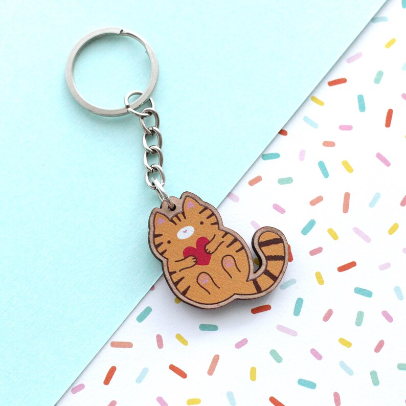 Wooden keychain of an orange tabby cat holding a heart