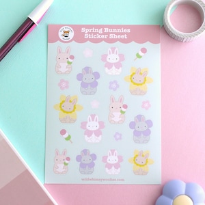 May include: A sticker sheet with the text "Spring Bunnies" features various bunny illustrations in pastel colors. The bunnies are surrounded by flowers and treats. The Wild Whimsy Woolies logo is in the upper left corner. The website wildwhimsywoolies.com is at the bottom.