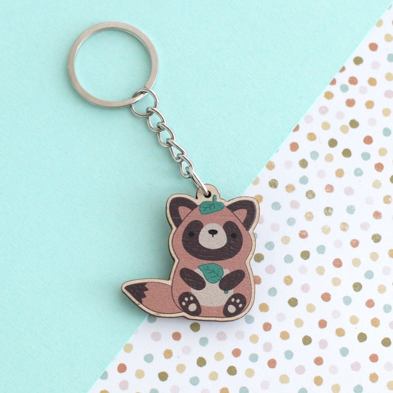 Wooden keychain of a tanuki (Japanese raccoon dog) holding a green leaf