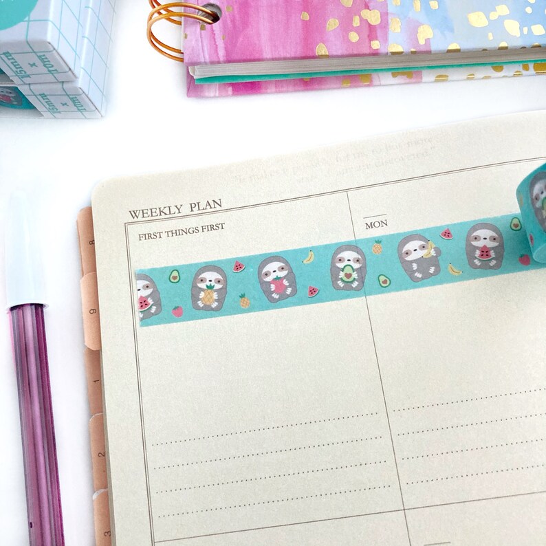 May include: A weekly planner with a blue and white washi tape featuring sloths eating fruit. The tape reads "First Things First" and is placed above the "Mon" column.