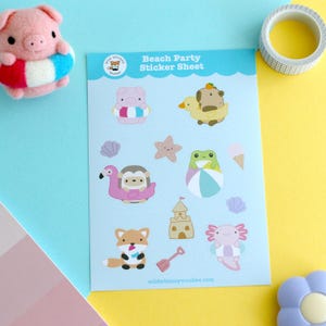 May include: A light blue sticker sheet with the text "Beach Party Sticker Sheet" featuring cartoon animals in beach-themed designs. Includes a pig in a floatie, a duck, a frog, a fox, and an axolotl. A roll of tape and a plush pig are also visible.
