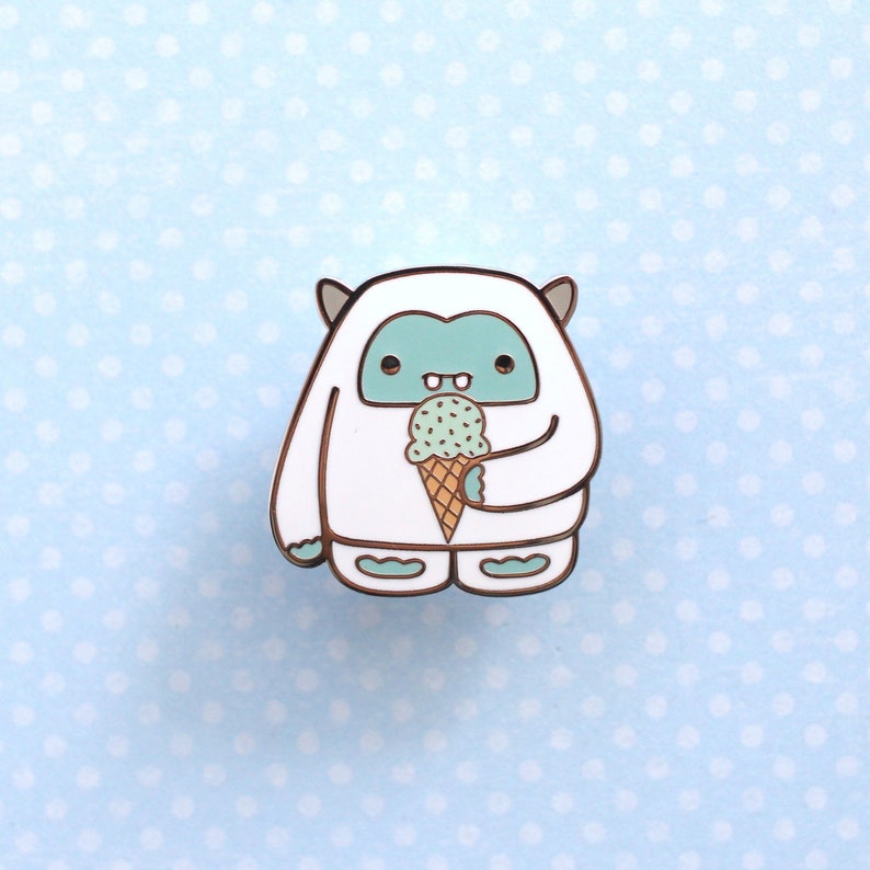 Enamel pin of a white and blue yeti enjoying a mint chocolate chip  ice cream