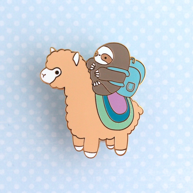 Large enamel pin of a sloth wearing a backpack and riding on top of an alpaca (or llama)