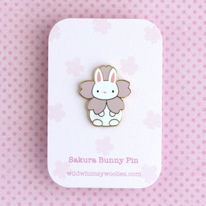 Backing card of an enamel pin of a little bunny wearing a pink sakura flower costume