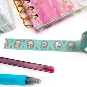 Desk with pencils, a notebook and a green washi tape featuring fruits and cute sloth holding fruits