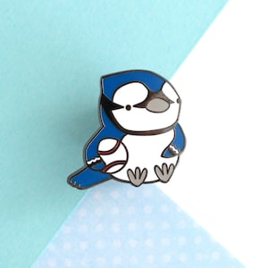 Può includere: Spilla smaltata blu con un pallone da baseball nell'ala. La spilla è bianca e blu con contorni neri.