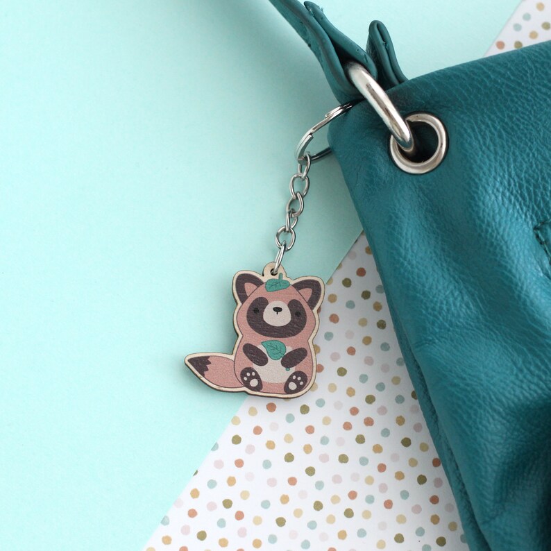 Green purse with a wooden charm of a tanuki holding a green leaf