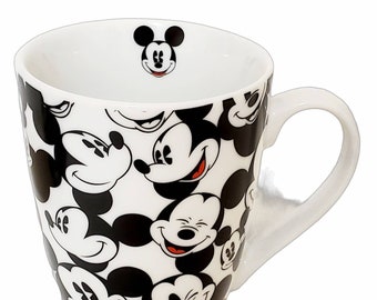 May include: White ceramic mug with a black and white Mickey Mouse pattern. The mug has a handle and is approximately 4 inches tall.