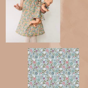 May include: A dress featuring a floral pattern with blue, pink, and green petals on a light blue background. The fabric is labeled HAPPY PETALS BLUE. The dress has short flutter sleeves and a round neckline, matching a smaller version for a doll.